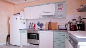 Una cocina moderna con armarios blancos y azul verdoso, horno empotrado, lavavajillas y varios utensilios de cocina.