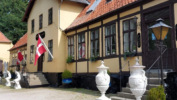 Un bâtiment traditionnel avec un toit en tuiles, un drapeau et un escalier menant à l’entrée.