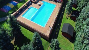 An aerial view of a property with a large rectangular swimming pool, surrounded by a wooden deck and a small patio area with outdoor seating. - 6 Person Holiday Park Home in Graested (Graested)