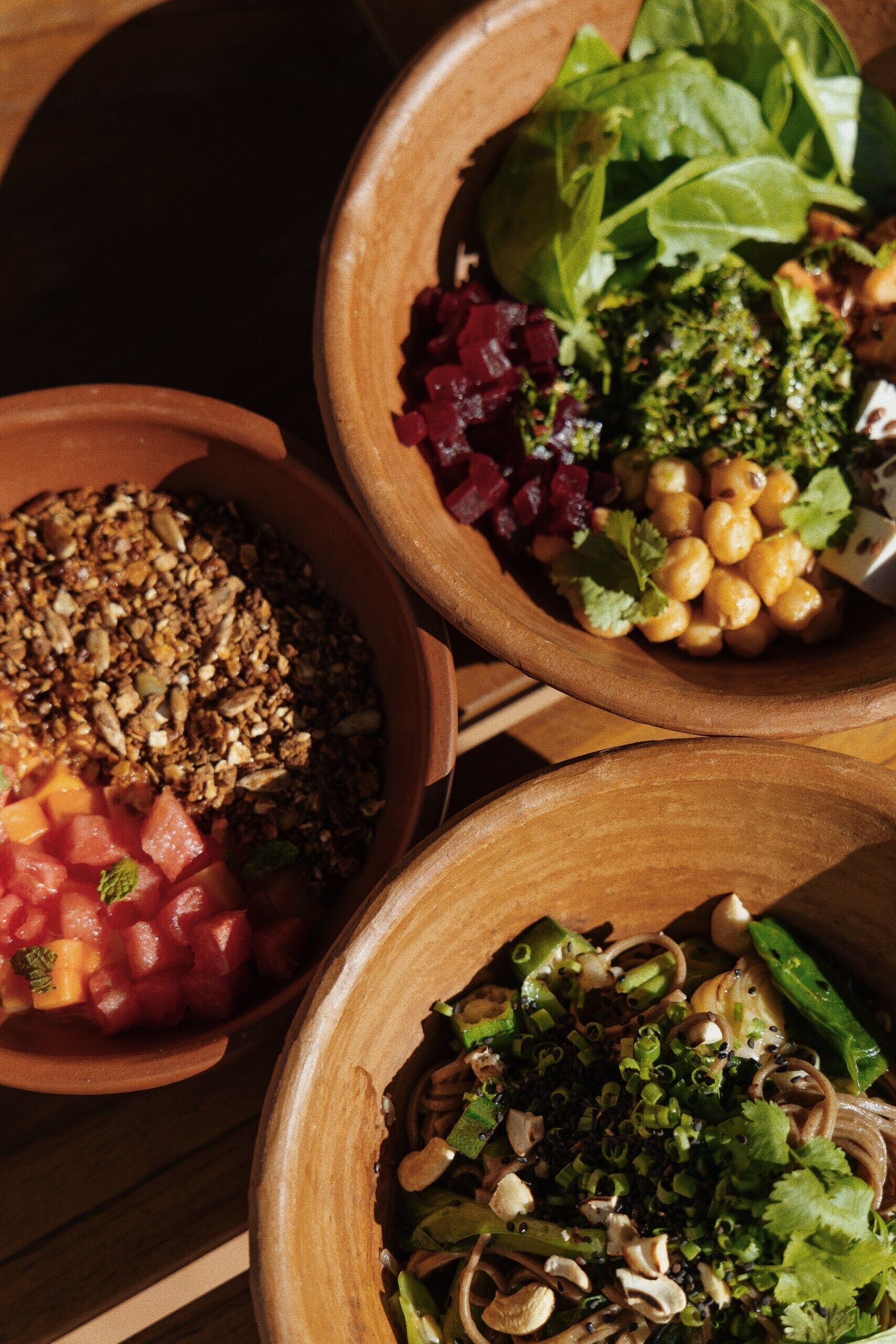 Three wooden bowls containing different dishes.