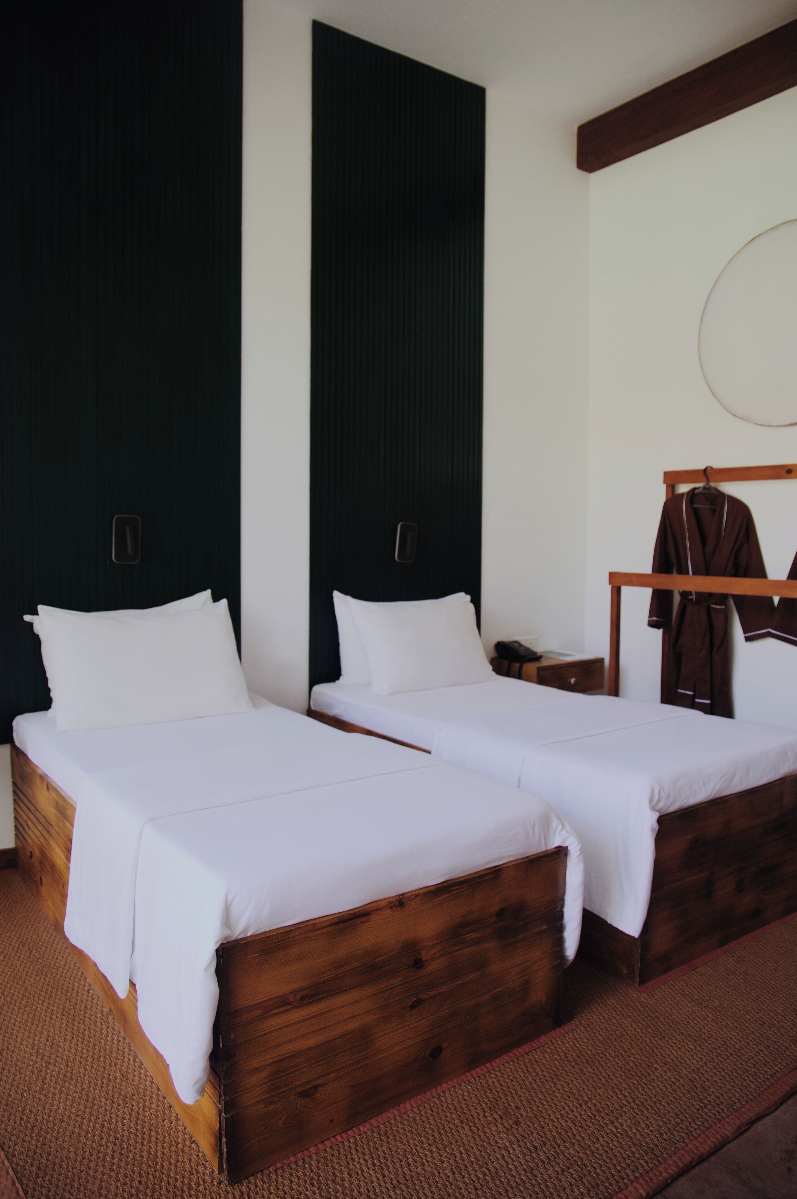 Two wooden beds with white linens in a room with dark wooden walls and a wooden ceiling beam.