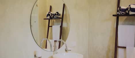 A bathroom with a round mirror, a white sink, and a towel rack.