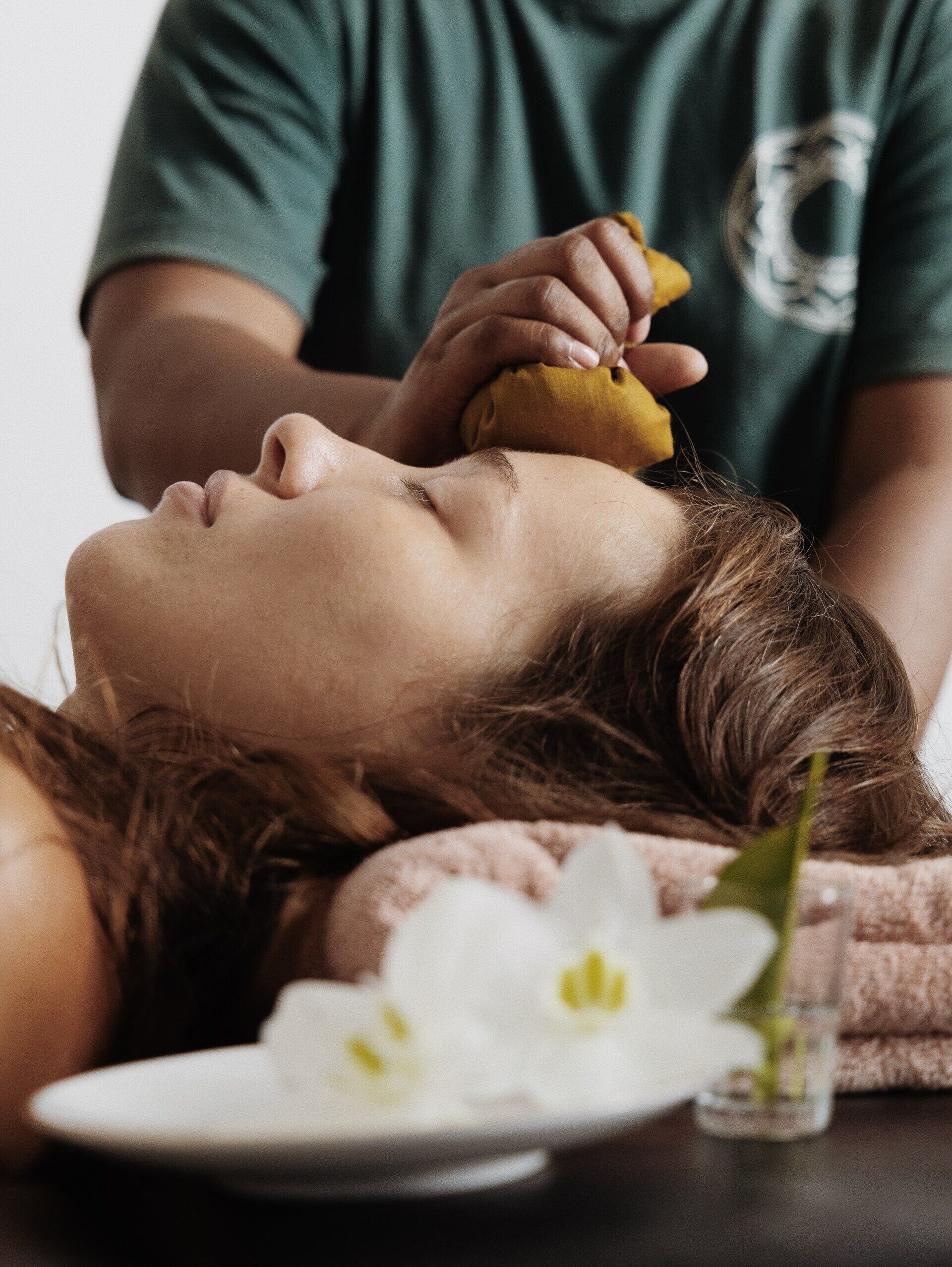Une personne reçoit un massage, une serviette est posée sur elle et un petit verre d’eau est placé sur une table à proximité.