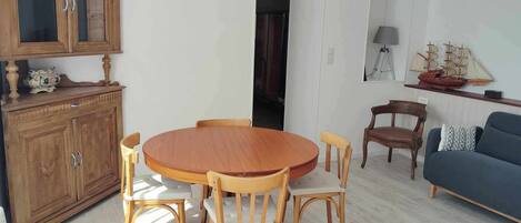 Un coin repas avec une table et des chaises en bois, un meuble avec des portes en verre et un luminaire suspendu.