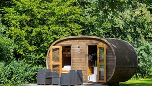 A wooden cylindrical cabin with an open door, a small porch with seating, and a number '22' sign. - 0 Person Holiday Park Home in Hesselager (Hesselager)