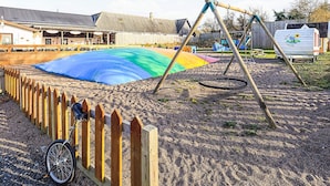 A sandy play area with a swing set and a bicycle leaning against a wooden fence. - 6 Person Holiday Park Home in Gorlev (Gørlev)