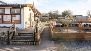 A building with a wooden staircase leading to a porch with outdoor seating. - 6 Person Holiday Park Home in Gorlev (Gørlev)