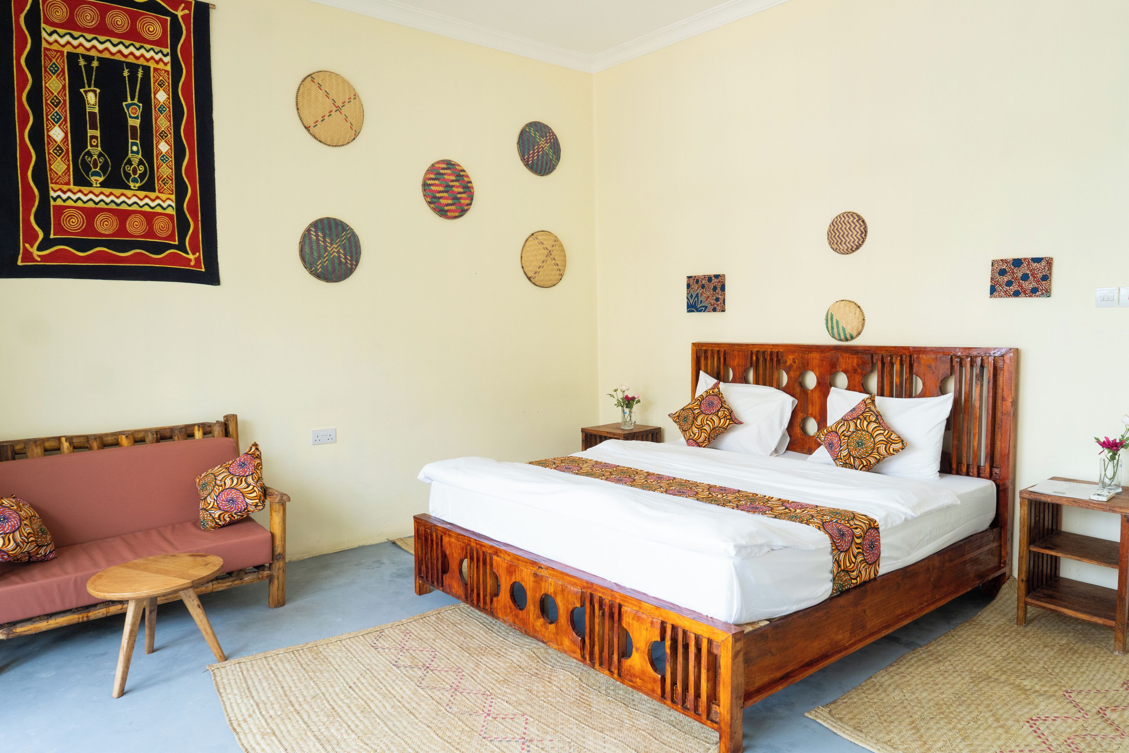 Una habitación con una cama de madera, un sofá y una pared decorada con elementos tejidos.
