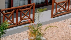 A building with a large glass door, wooden railings, and a gravel pathway with plants. - Andy's Inn Michamvi (Michamvi)