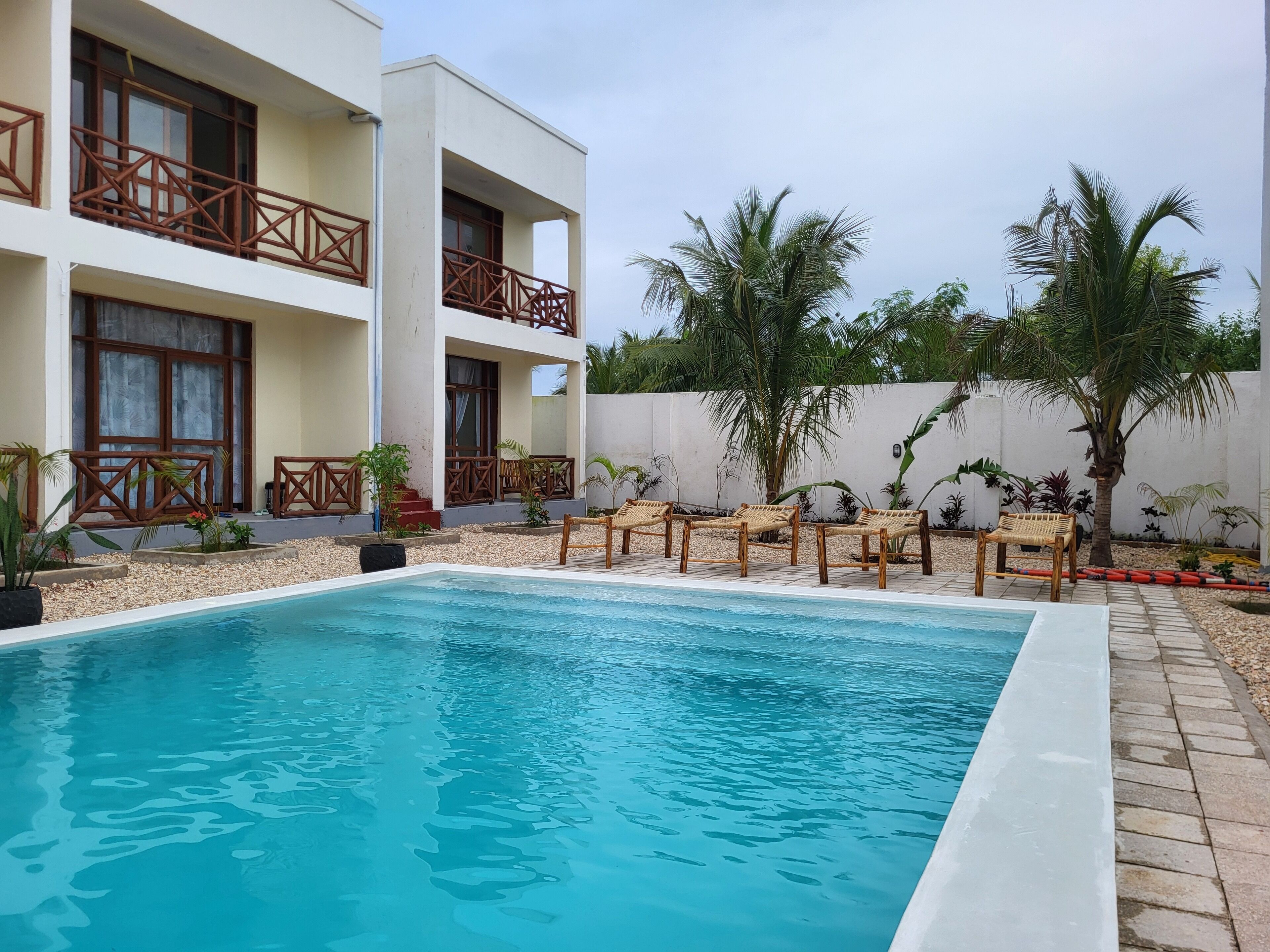 A swimming pool with lounge chairs and palm trees in a resort setting.