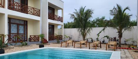 A swimming pool with lounge chairs and palm trees in a resort setting.