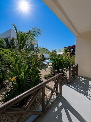 A sunny outdoor area with a pool, palm trees, and a wooden fence. - Andy's Inn Michamvi (Michamvi)