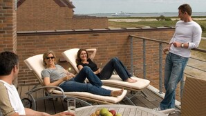 En balkon med to liggestole, et bord med frugt og havudsigt.