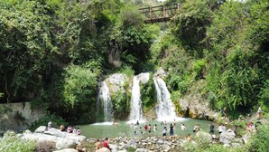 Un cadre naturel avec une cascade et des personnes qui profitent de l’eau.