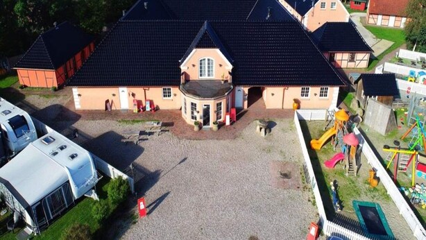 A large building with a central entrance, surrounded by a gravel area and a playground. - 6 Person Holiday Park Home in Graested (Graested)