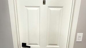 A white door with a black number plate indicating room 3, a black door handle, and a brown doormat.