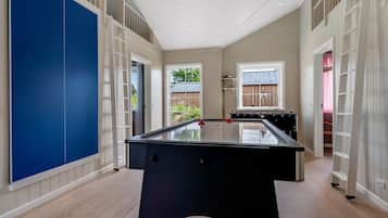 Une pièce spacieuse avec une table de billard, un plancher en bois et une vue sur l’extérieur.