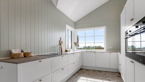 A modern kitchen with white cabinetry, a large window, and a view of the outdoors. - "Adia" - 650m from the sea by Interhome (Ebeltoft)
