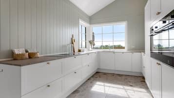 Une cuisine moderne avec des meubles blancs, une grande fenêtre et une vue sur l’extérieur.