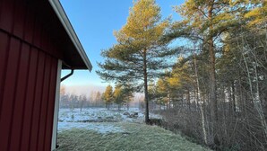 A red building with a sloped roof, surrounded by a snowy landscape and a dense forest. - 2 Person Holiday Park Home in Orsa (Orsa)