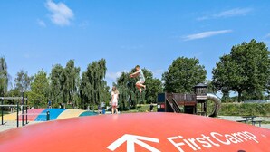 A playground with a red slide and a First Camp logo. - 6 Person Holiday Park Home in Bogense (Bogense)