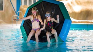 Zwei Kinder nutzen eine große, schwarz-blaue Wasserrutsche im Pool.
