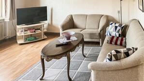 A living room with a sofa, a coffee table, and a television on a stand. - 2 bedroom stunning home in Harboøre (Harboøre)