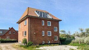A two-story brick building with a sloped roof, multiple windows, and a small balcony. - 2 bedroom stunning home in Harboøre (Harboøre)