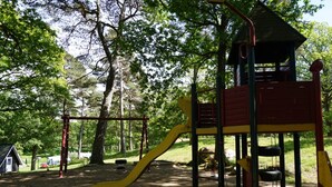 A playground with a yellow slide, red and yellow climbing structures, and a small shelter. - 2 Person Holiday Park Home in Stenungsund (Stenungsund)