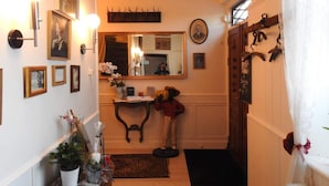 A hallway with framed pictures, a mirror, a small table with a vase of flowers, and a door with a coat rack. - 2 Person Holiday Park Home in Tranekaer (Tranekaer)