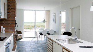 Een moderne keuken met een groot raam, een eethoek met stoelen, en uitzicht op de omgeving.