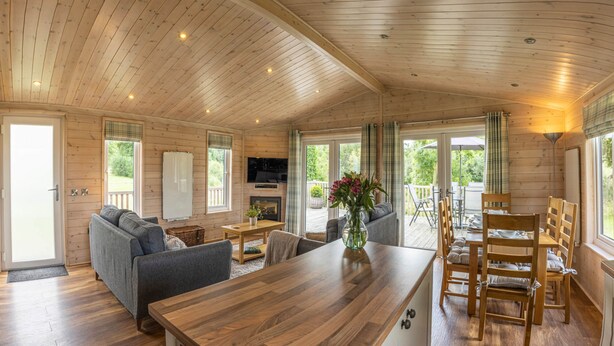 Ein Holzblockhaus-Interieur mit Essbereich, Sofa und Kamin.