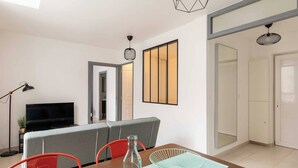 A modern living room with a dining area, a flat-screen TV, and a large window. - DIFY Berlioz - Charpennes (Villeurbanne)