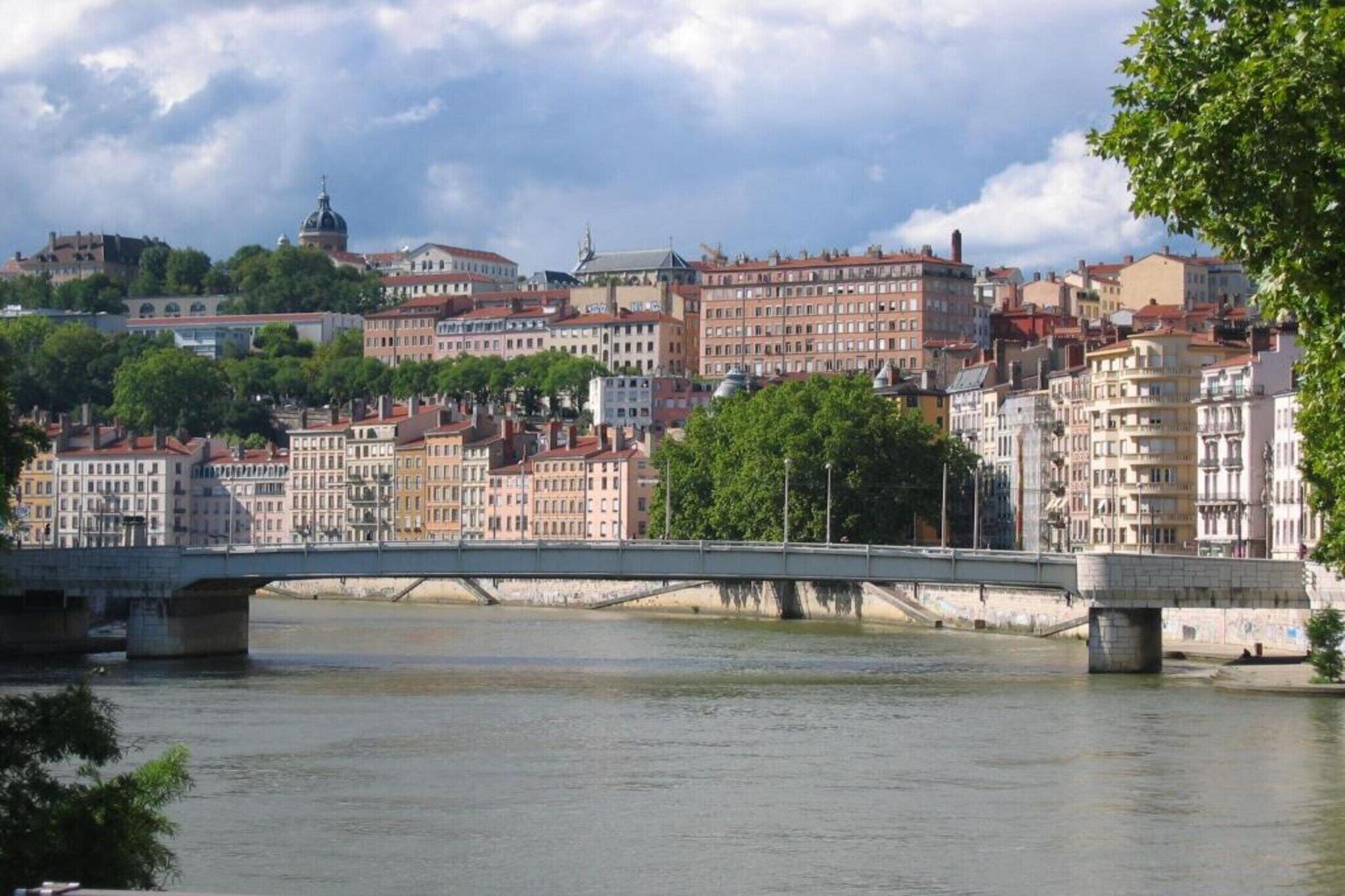A bridge over a river with buildings in the background.