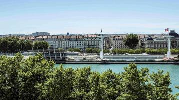 A waterfront cityscape with historic buildings, a modern bridge, and a flag on a tall structure.