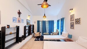 A bedroom with a bed, a chair, a small table, and a bookshelf. - Heritage Haven Luxury Spacez Villa (Bengaluru)