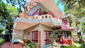 A two-story house with a balcony, potted plants, and a red door. - Heritage Haven Luxury Spacez Villa (Bengaluru)