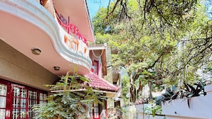 A courtyard with a small garden, a red door, and a white wall. - Heritage Haven Luxury Spacez Villa (Bengaluru)