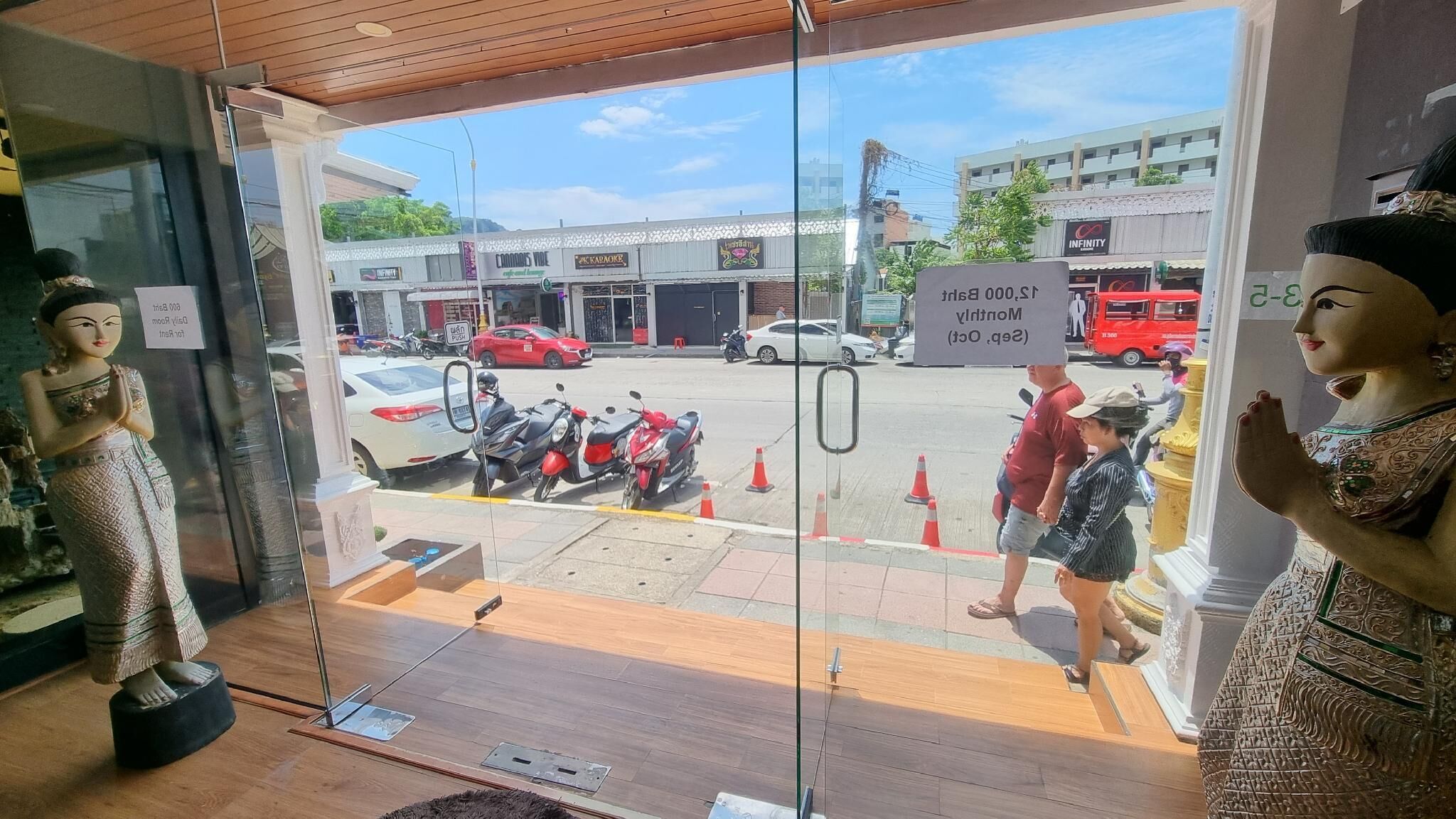 A storefront with glass doors, a statue of a woman on the left, and another statue on the right.