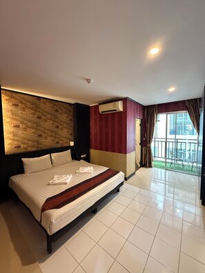 Habitación de hotel con una cama grande, aire acondicionado, vista al exterior y un balcón.