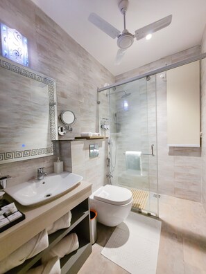 Un baño moderno con cabina de ducha de vidrio, tocador con lavabo e inodoro.