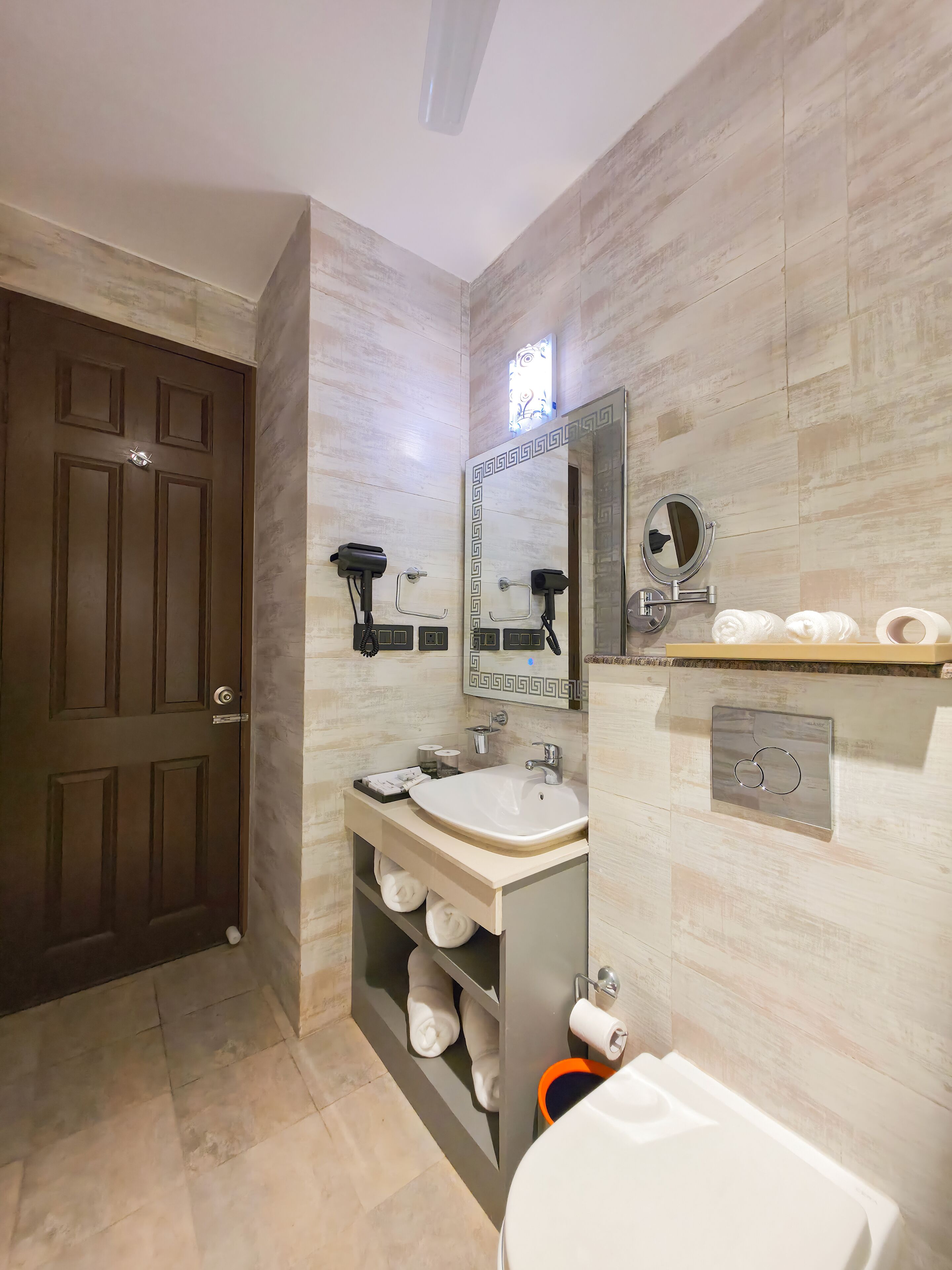 A modern bathroom with a large mirror, a sink, a toilet, and a towel rack.