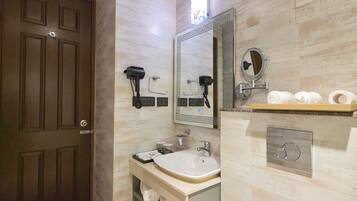 A modern bathroom with a large mirror, a sink, a toilet, and a towel rack.