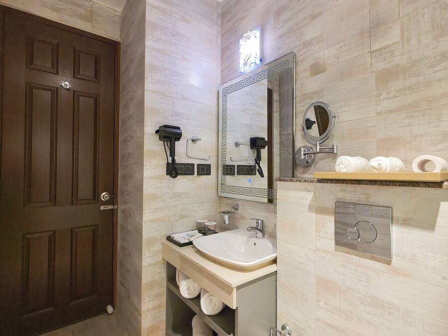 A modern bathroom with a large mirror, a sink, a toilet, and a towel rack.
