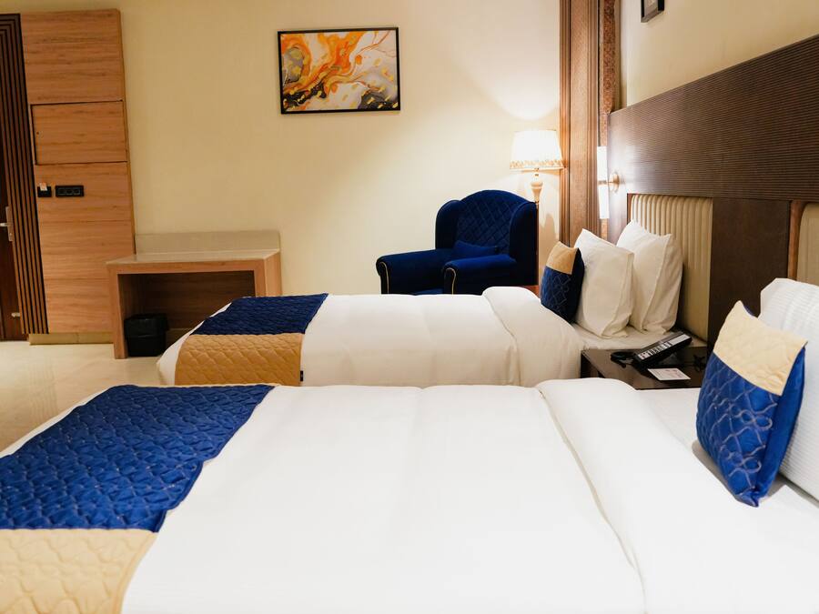 Una habitación de hotel con dos camas, un escritorio, una silla y un cuadro en la pared.