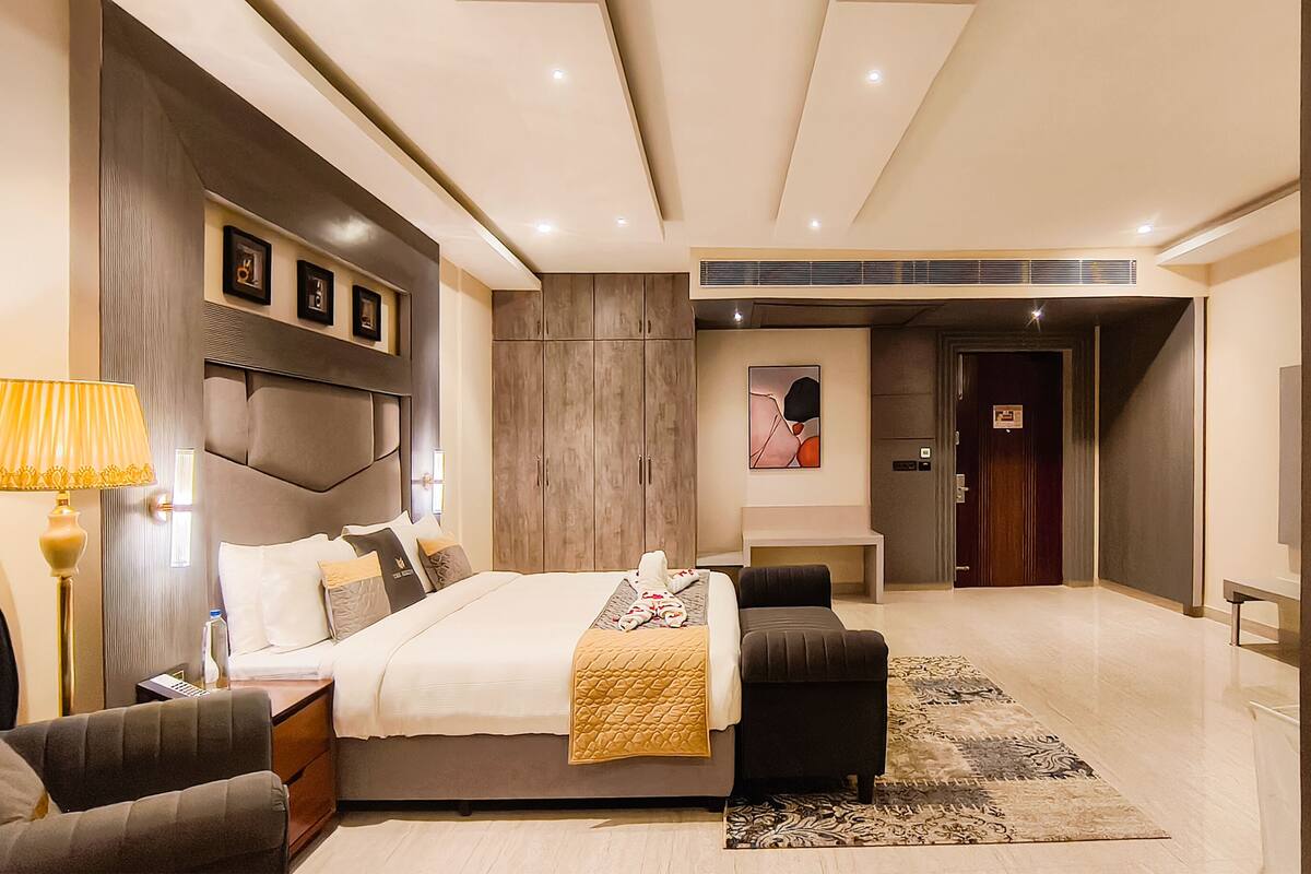 Ein modernes Hotelzimmer mit einem großen Bett, Nachttischen, einem Schreibtisch und einem Kleiderschrank.