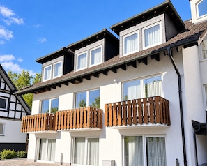 A two-story building with a balcony, large windows, and a sloped roof.