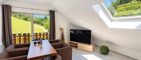 Una sala de estar moderna con televisión, sofá y mesa de comedor.