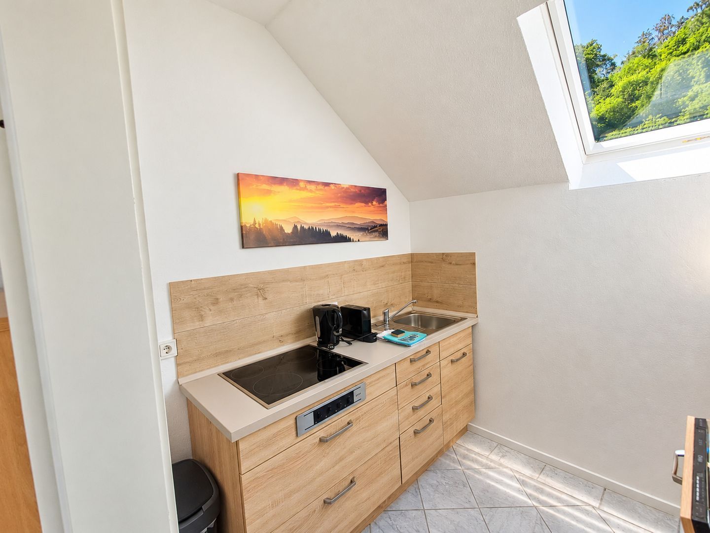 A compact kitchen with a built-in stove, a coffee maker, and a sink.