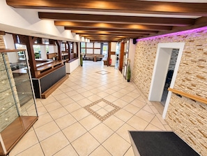 A hotel lobby with a reception desk, a seating area, and a stone wall.